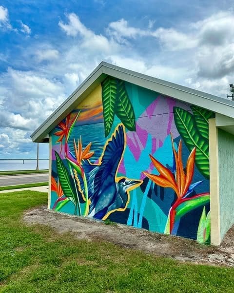 Tropical mural in bold blue and green colors on the back of a shed