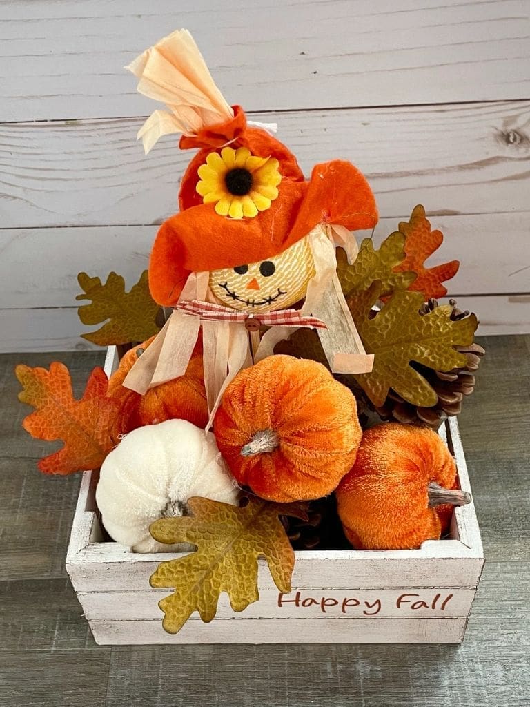 wooden white crate full of mini pumpkins, apples and a scarecrow