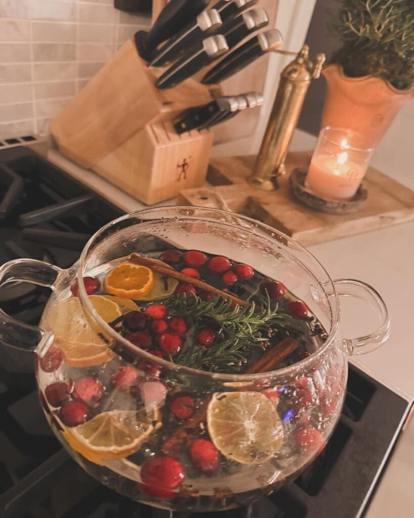 simmer pot full of oranges, herbs and berries on a stove top simmering for a festive smell at Thanksgiving
